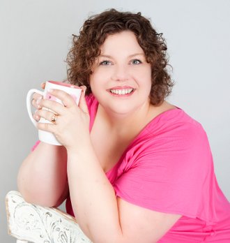 Carla Anne Coroy - Carla Anne in pink top on white chair holding coffee mug